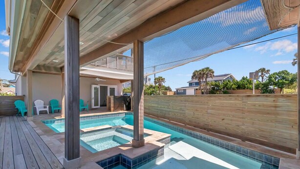 A swimming pool with a wooden deck, a covered area, and a view of the neighborhood. - Salt Therapy N - Coastal escape w/ beach access (St Augustine)