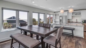 A modern kitchen with white cabinets, a large island, and pendant lighting. - Salt Therapy S - Stylish retreat w/ beach & pool (St Augustine)