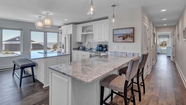 A modern kitchen with white cabinets, a marble island, and pendant lighting. - Salt Therapy S - Stylish retreat w/ beach & pool (St Augustine)