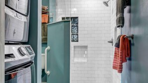 Un baño compacto con ducha, horno empotrado y refrigerador.