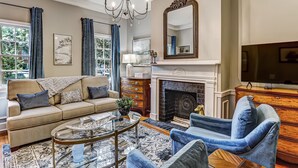 A living room with a sofa, armchairs, a coffee table, a fireplace, and a television.