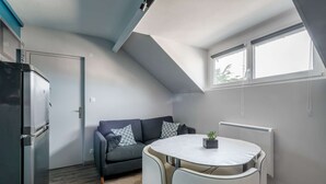 A compact living space with a kitchenette, a sofa, a dining table, and a radiator.