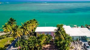 A coastal property with a view of the ocean, palm trees, and a building with a flat roof. - Dolfan Oceanfront Cottage Direct oceanfront with 50 ft of dockage and jacuzzi and kayaks 4 bed 2 bath home (Marathon)