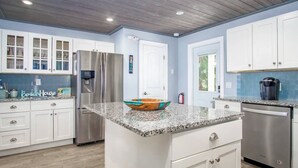 A modern kitchen with white cabinetry, a granite countertop, stainless steel appliances, and a decorative bowl centerpiece. - Dolfan Oceanfront Cottage Direct oceanfront with 50 ft of dockage and jacuzzi and kayaks 4 bed 2 bath home (Marathon)