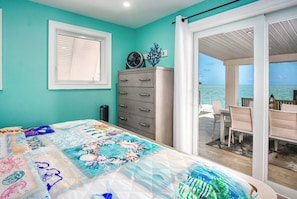 Un dormitorio con cama, cómoda, ventana y vista al océano.