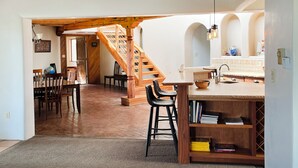Une cuisine spacieuse avec un escalier en bois, un coin repas et un bar avec des tabourets.