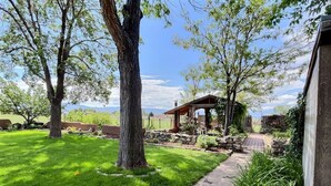 Un jardin bien entretenu, agrémenté d’un chemin en pierre, d’une pergola en bois et d’un mur en pierre.