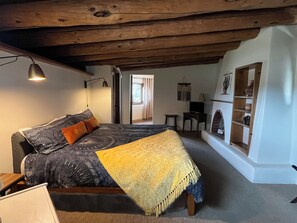 Une chambre à coucher avec un lit, un bureau, une télévision et une cheminée.
