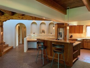 A spacious kitchen with a large island, wooden accents, and a rustic ceiling.