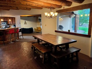 Una cocina con una mesa de madera y bancos, una barra y vistas al exterior a través de una ventana.