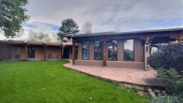 A house with a covered patio, a lawn, and a view of the mountains.