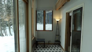 A narrow hallway with a patterned floor, large windows, and a standing lamp. - Spacious Shredder`s Lounge (Taos Ski Valley)