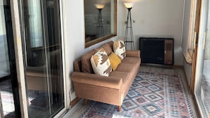 A living room with a brown sofa, patterned cushions, a large mirror, a standing floor lamp, and a radiator. - Spacious Shredder`s Lounge (Taos Ski Valley)