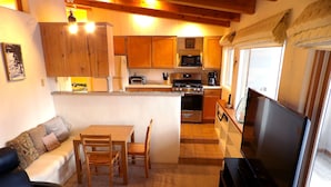 A compact living space with a kitchenette, a dining area, a sofa, and a TV. - Spacious Shredder`s Lounge (Taos Ski Valley)
