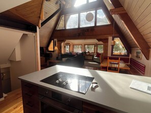 Uma cozinha com fogão, uma sala de jantar com mesa e cadeiras, e uma sala de estar com sofá e mesa de centro.