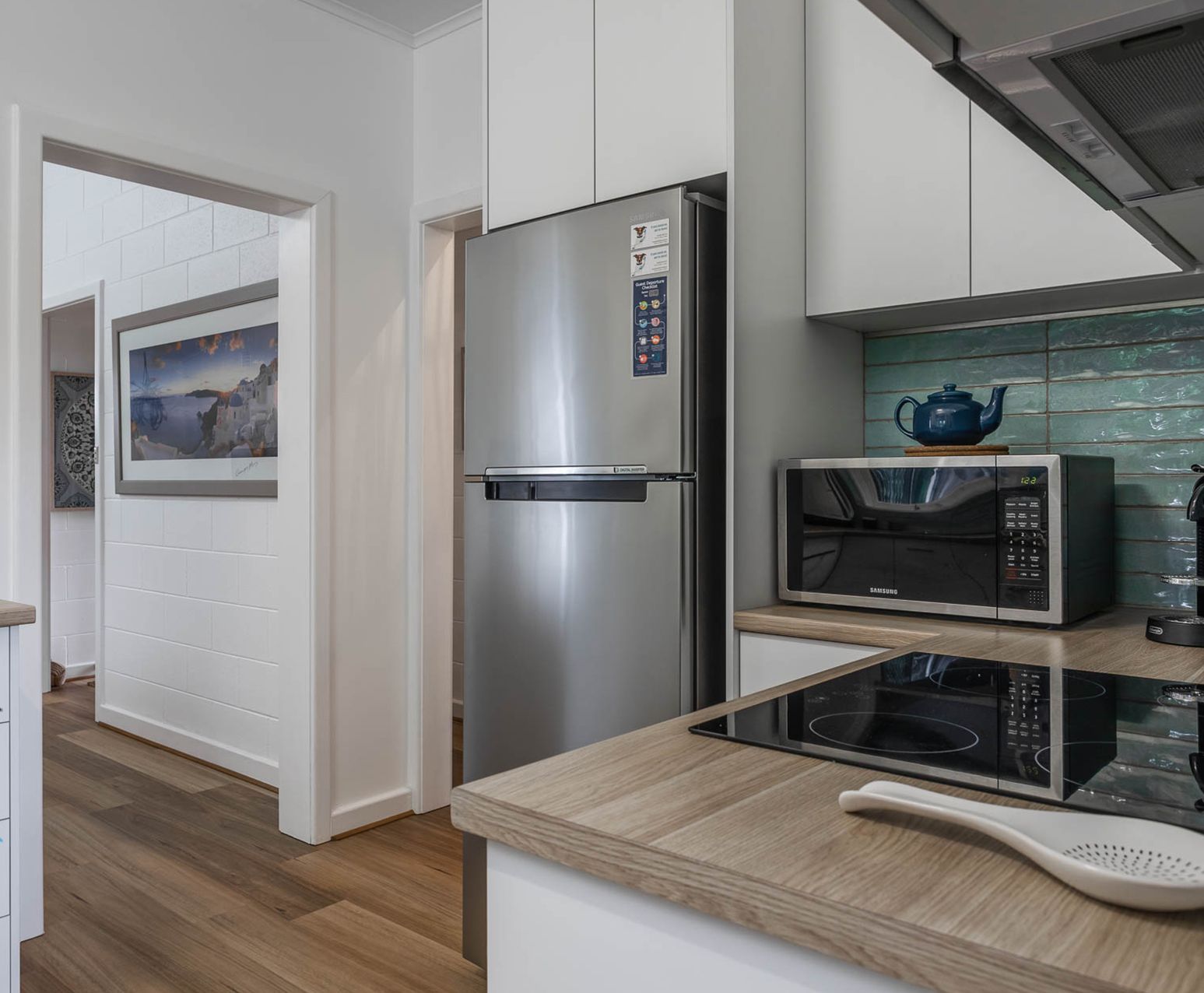 A modern kitchen with a stainless steel refrigerator, a microwave, and a wooden countertop.
