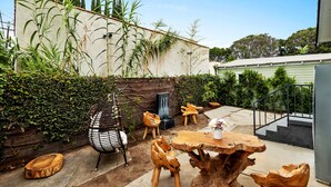 Un patio rústico al aire libre con mobiliario de madera, una mesa de piedra y una silla de madera.