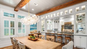 A spacious kitchen with white cabinetry, a wooden dining table, and a hanging light fixture. - WaterColor Dream: Bikes, Electric Cart, WaterColor Beach Club Access, and Private Pool. (Santa Rosa Beach)