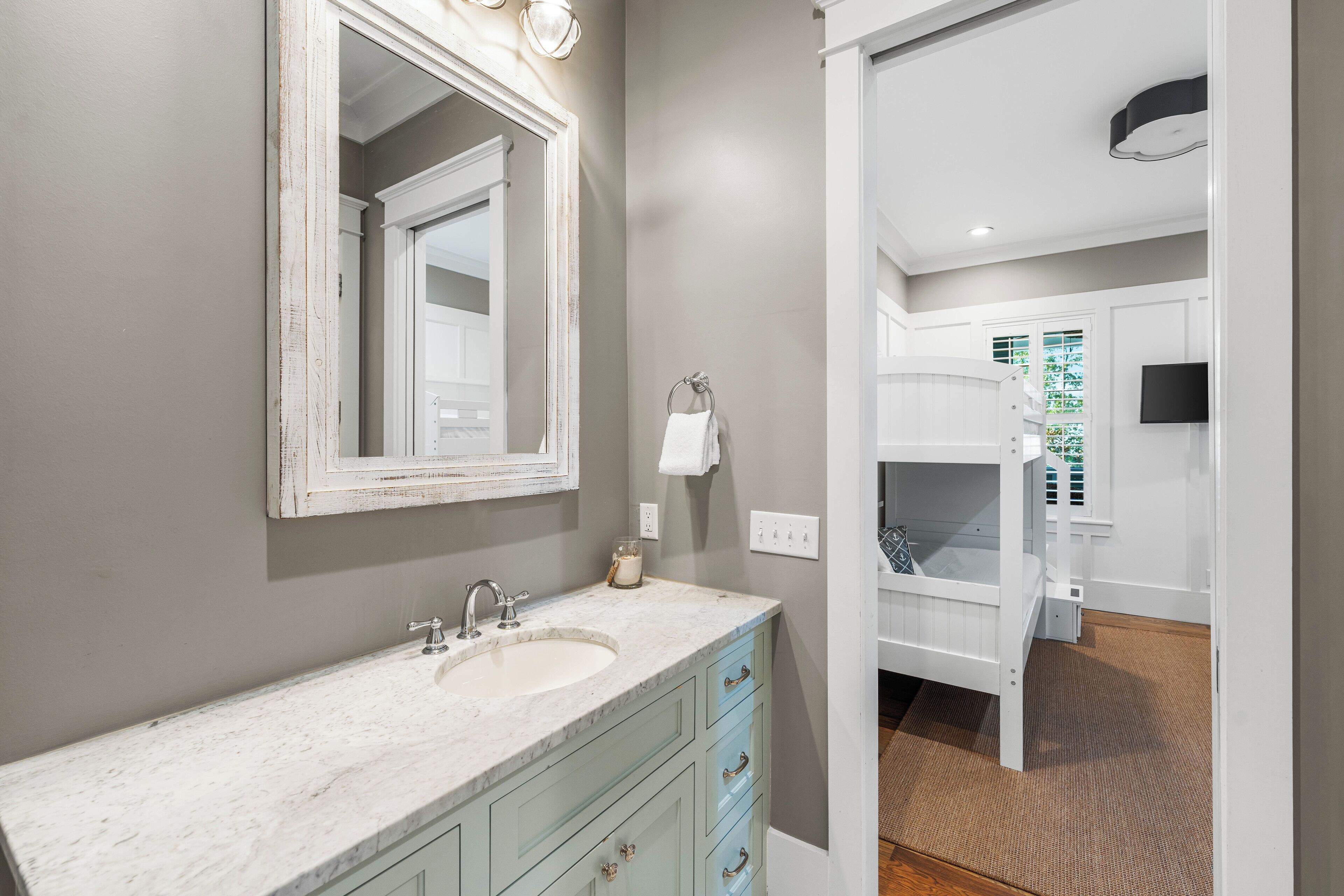 A bathroom with a marble sink, a large mirror, and a white vanity.