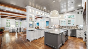 A spacious kitchen with white cabinetry, a large island, and a dining area with a view of the outdoors. - WaterColor Dream: Bikes, Electric Cart, WaterColor Beach Club Access, and Private Pool. (Santa Rosa Beach)