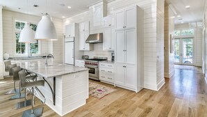 Una cocina amplia con armarios blancos, una isla grande y electrodomésticos modernos.