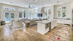 Una cocina amplia con una isla grande, armarios blancos y un comedor con sofá y mesa de centro.