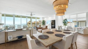 Ein geräumiger Wohnbereich mit einem großen Holztisch, weißen Sofas und einem Kronleuchter.