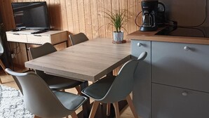 Eine moderne Küche mit einem Holzespeisetisch, grauen Stühlen, einer Mikrowelle und einer Kaffeemaschine.