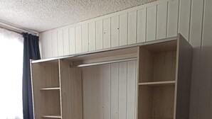 Ein Zimmer mit einem Holzschrank, einem grauen Stuhl und einem dunklen Teppich.