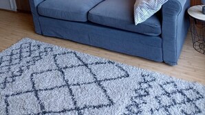 Ein blaues Sofa mit roten und weißen Kissen, ein gemustertes Teppich und eine Holzwand.