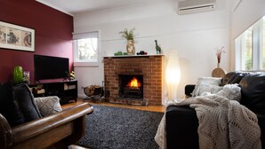 Ein Wohnzimmer mit Kamin, Fernseher und einer Couch.