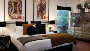 Ein modernes Schlafzimmer mit einem großen Bett, schwarz-weißer Bettwäsche, einer braunen Tagesdecke und zwei abstrakten Bildern an der Wand.