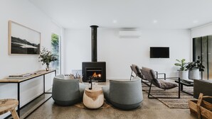 Un salon moderne doté d’une cheminée, de sièges confortables et d’un téléviseur à écran plat.