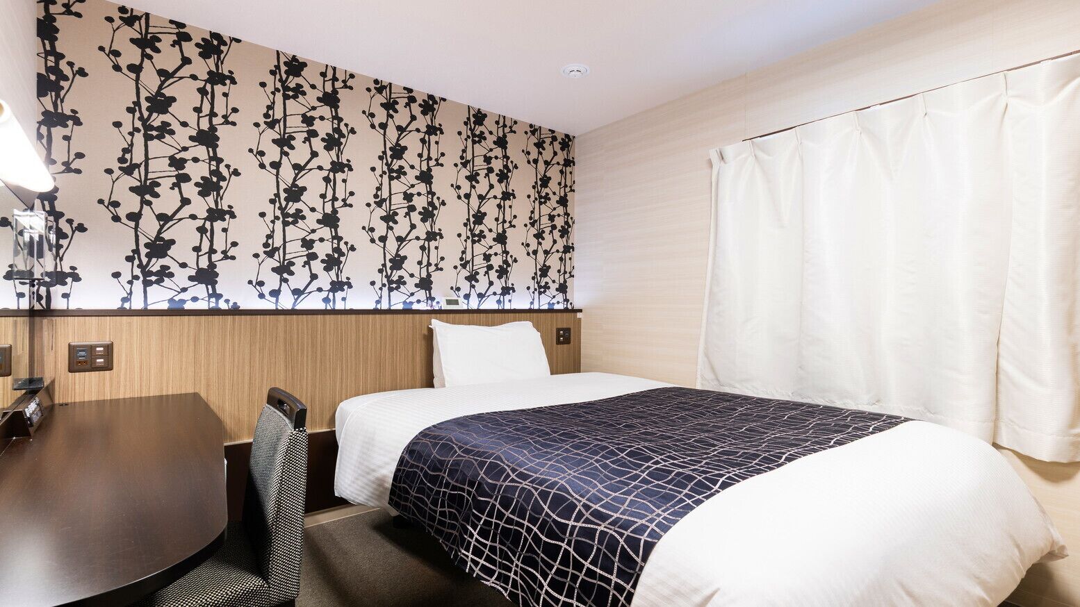 A hotel room with a bed, a desk, and a chair.