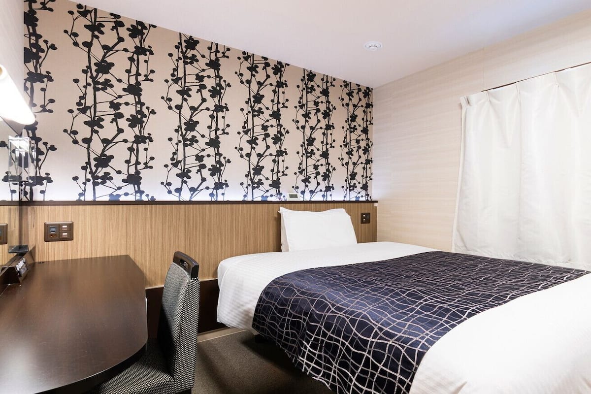 Ein Hotelzimmer mit Bett, Schreibtisch und Stuhl.