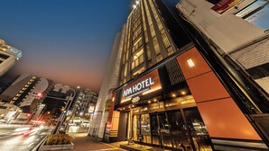 Een hotel met een opvallend bord, een moderne gevel en uitzicht op de straat.