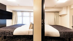 Een hotelkamer met twee bedden, een flatscreen televisie, een groot raam met gordijnen en een vloerbedekking.