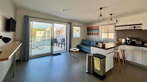 A modern apartment with a kitchen, dining area, and a balcony with a view.