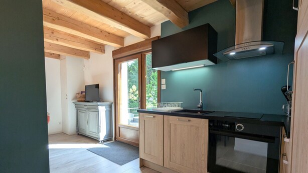 A modern kitchen with wooden cabinets, a built-in oven, and a window overlooking greenery. - Quiet & Elegant Getaway: Modern Farmhouse with Terrace, Trails & No Overlook (Le Tholy)