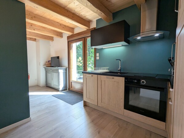 Una cocina moderna con armarios de madera, horno empotrado y ventana con vistas a zonas verdes.