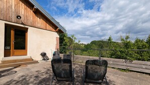 A wooden building with a door and a grill outside. There are two chairs in front of the building. - Quiet & Elegant Getaway: Modern Farmhouse with Terrace, Trails & No Overlook (Le Tholy)