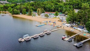 An aerial view of a lakeside property with a dock, boats, and a small building. - Hauts-Bois Ski In/Out 2brs w/Pool Access (193-1) (Mont-Tremblant)