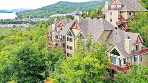 A cluster of multi-story houses with steeply pitched roofs, wooden balconies, and large windows. - Hauts-Bois Ski In/Out 2brs w/Pool Access (193-1) (Mont-Tremblant)