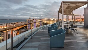 A terrace with outdoor seating, a railing, and a view of the cityscape and water. - Eurostars Universal Lisboa (Lisbon)
