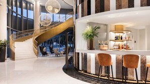 A modern hotel lobby with a curved staircase, a bar area with stools, and a large potted plant. - Eurostars Universal Lisboa (Lisbon)