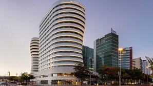 A modern hotel with a curved facade, multiple floors, and a prominent Eurostars logo. - Eurostars Universal Lisboa (Lisbon)