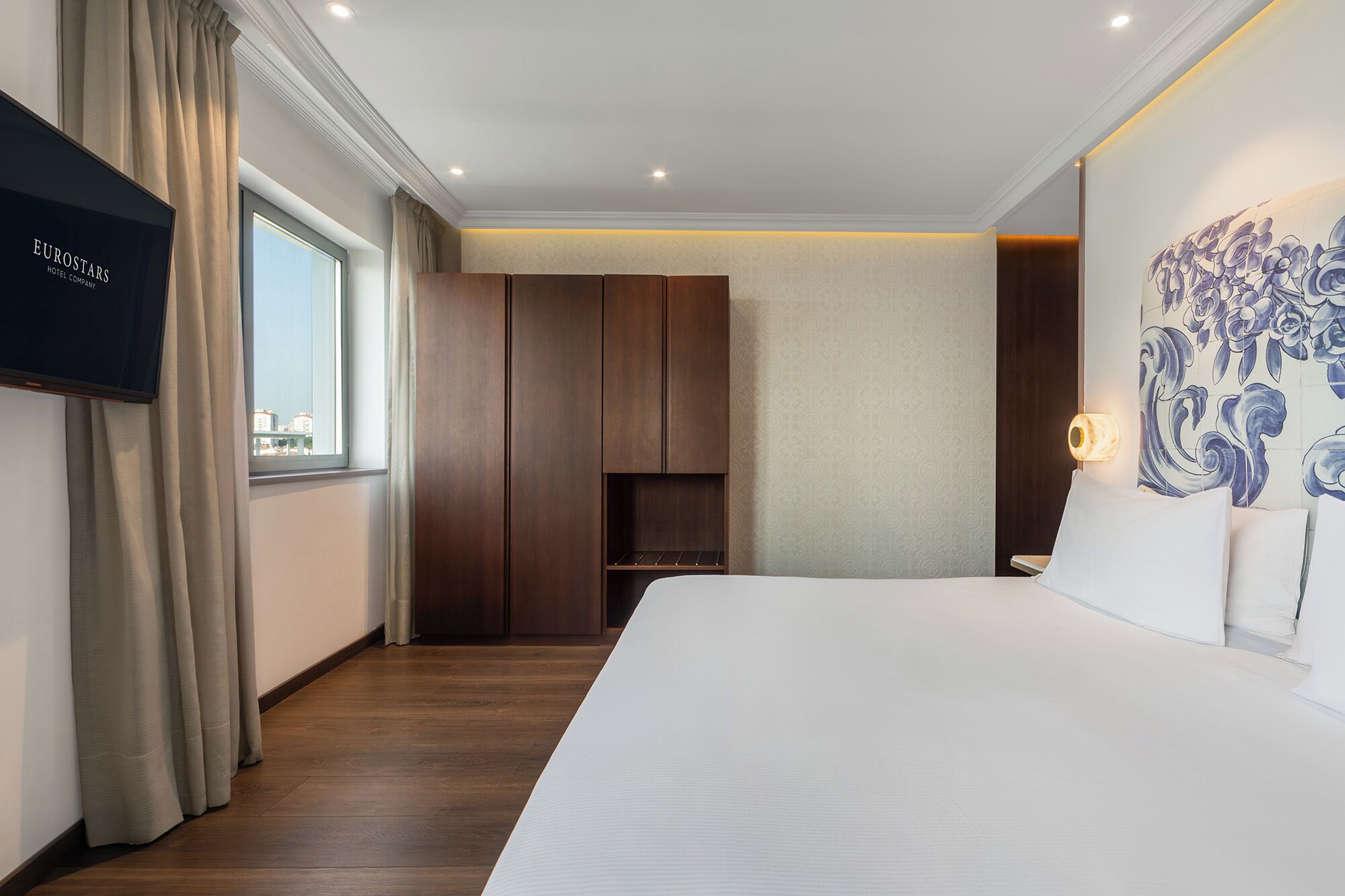 Une chambre d’hôtel avec un grand lit, une armoire, une télévision et un tableau au mur.