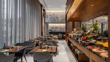 A restaurant with a buffet, dining tables, and chairs.