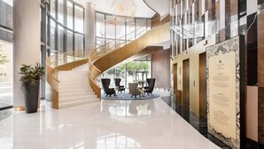 A spacious lobby with a curved staircase, a reception desk, and a large potted plant. - Eurostars Universal Lisboa (Lisbon)