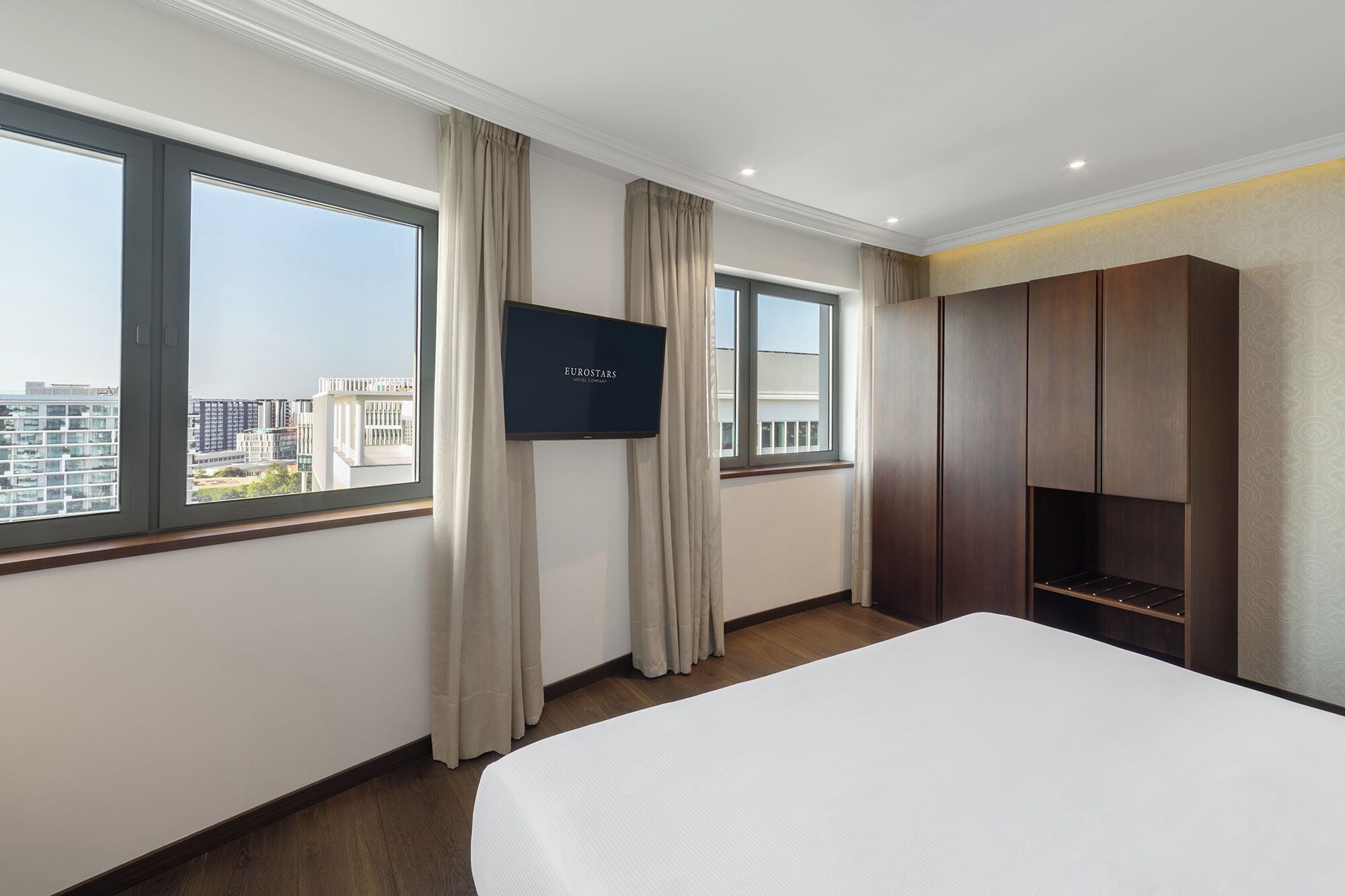 Una habitación de hotel con una cama grande, un televisor de pantalla plana y un armario.